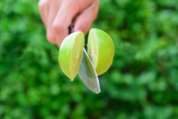 The man use knife split the fresh green lemon in midair