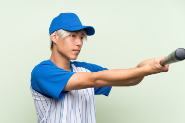 Wall Mural - Young asian man playing baseball over isolated green background