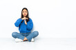 © luismolinero - Young mixed race woman sitting on the floor isolated on white background making time out gesture