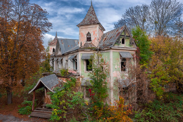 Abandoned house of the 19th century in Victorian style in the dense autumn forest. Aerial side view. 