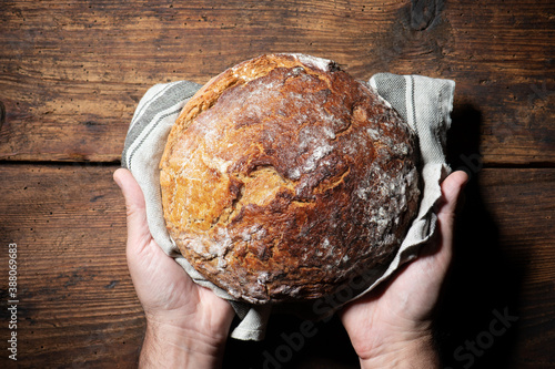 Fotografía Baker's hands holding and presenting fresh baked loaf of bread
