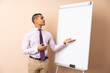 © luismolinero - Young business man over isolated background giving a presentation on white board