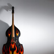 Acoustic double bass with flames decals, close-up view. Rock'n'roll, rockabilly musical instrument in studio background shot in low key