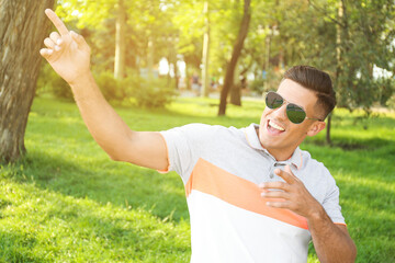 Wall Mural - Handsome man wearing stylish sunglasses in park