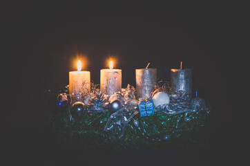 two advent candles burning on black background