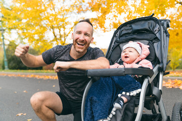 Wall Mural - man with her daughter standing in jogging stroller outside in autumn nature