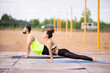 © Georgii - Pilates or yoga workout of young couple in stylish sportswear outdoor on sports mats, healthy lifestyle in urban