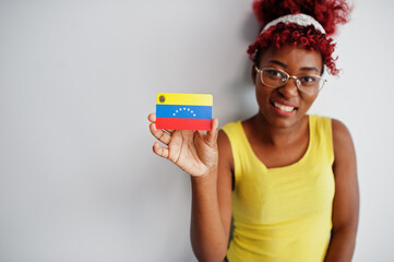 Wall Mural - African american woman with afro hair, wear yellow singlet and eyeglasses, hold Venezuela flag isolated on white background.