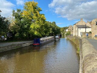 Wall Mural - Boats, on the canal, with old trees, houses, and a blue sky in, Skipton, Yorkshire, UK