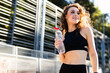 Healthy and sporty young woman drinking water from the bottle after doing sport outdoor.