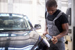© alfa27 - car detailing and polishing concept. young african professional car service male worker, auto mechanic with orbital polisher,automobile concept