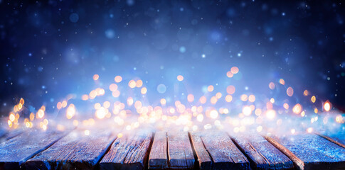 Wall Mural - snowy wooden table with defocused lights - abstract christmas background
