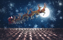 Santa Claus On His Sleigh, Pulled By Reindeer, Flying At Night To Deliver Gifts