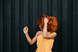 © Daniel Sierralta/Westend61 - Cheerful young woman shaking hair while standing against wall