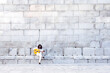 © Jose Luis CARRASCOSA/Westend61 - Flamenco guitarist playing guitar while sitting on bench against concrete wall