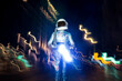© Jose Luis CARRASCOSA/Westend61 - Male astronaut wearing space suit standing amidst light paintings on street at night