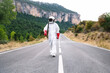 © Jose Luis CARRASCOSA/Westend61 - Male astronaut wearing space suit walking on road against mountain