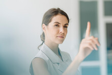 Young Woman Pointing On Glass Wall While Standing At Office