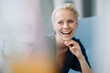 © KNSY/Westend61 - Close-up of businesswoman with hand on chin laughing while sitting in office