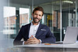 © Rainer Berg/Westend61 - Smiling businessman with hands clasped sitting by desk in office