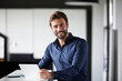 © Rainer Berg/Westend61 - Smiling businessman using digital tablet while standing at desk in office