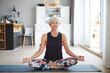 © Rainer Berg/Westend61 - Active senior woman meditating on exercise mat at home