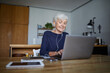 © Rainer Berg/Westend61 - Active senior working on laptop while listening music sitting at home