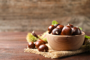 Wall Mural - Fresh sweet edible chestnuts on brown wooden table, closeup. Space for text