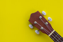 Closeup Top View Shot Of A Wooden Ukulele With Space For Text On A Yellow Background