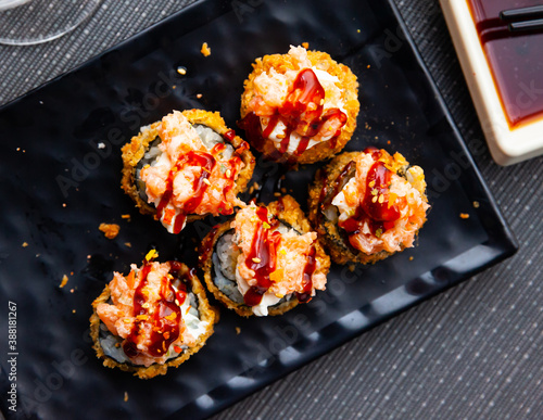 Cuadros en Lienzo Appetizing battered deep-fried futomaki with cream cheese and salmon served on black plate with soy sauce