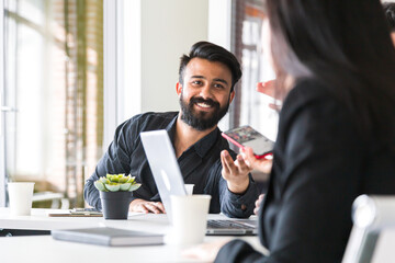 portrait of young Indian businessman in a business suit sitting at a table in a meeting