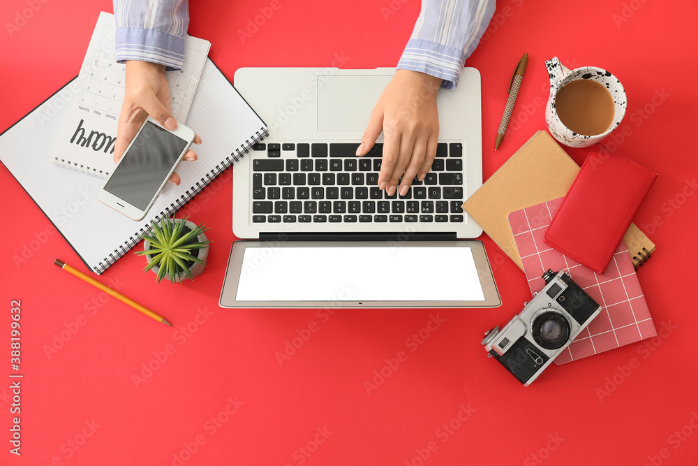 Female hands with modern laptop and mobile phone on color background
