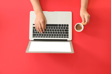 Female hands with modern laptop and cup of coffee on color background