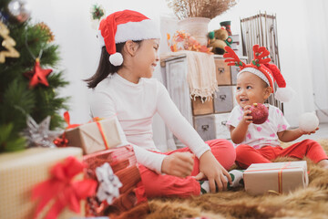 Wall Mural - cheerful cute childrens girls with gifts. kids wearing pajamas having fun near tree in the morning. merry christmas and happy holidays.  loving family with presents in room.