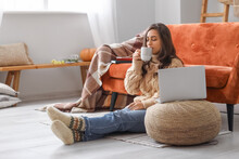 Beautiful Young Woman With Laptop And Cup Of Tea At Home