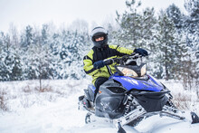Man Driving Snowmobile In Snowy Forest. Man On Snowmobile In Winter Mountain. Snowmobile Driving