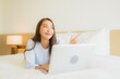 © siraphol - Portrait beautiful young asian woman use computer laptop on bed