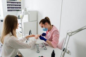 Female manicure master in a beauty salon work with hands of the client