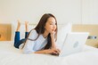 © siraphol - Portrait beautiful young asian woman use computer laptop on bed