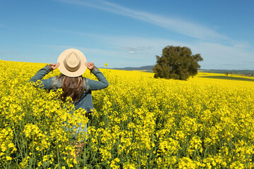 Female in denim jacket and shorts  in a field of flowering canola