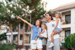 © Алина Битта - Beautiful family portrait, mom, father, small daughters, smiling outside next to their new house with sunset. Consept of new life in new house, life achivements.