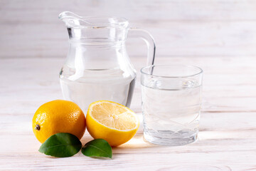 Wall Mural - Glass of water with lemon on white wooden table