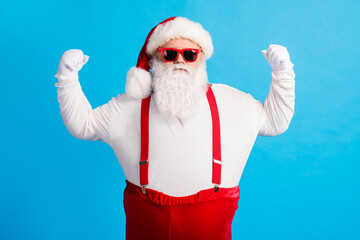 Sticker - Photo of confident santa claus with big stomach show hands muscles x-mas christmas fairy magic strength wear headwear sunglass overalls suspender isolated over blue color background