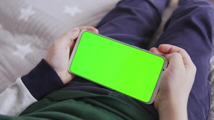 Poster - green screen in hand with a for keying Close-up playing a game The child is holding a Smartphone