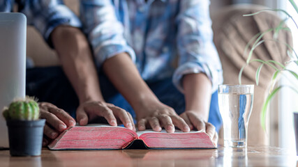 Wall Mural - Close up the Bible on wooden desk with hands reading in background, church in home, Home church during quarantine coronavirus Covid-19, Religion concept.