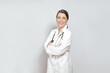Friendly smiling female doctor in a white lab coat, light background, copy or text space.