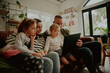 © StratfordProductions - Young family children using laptop computer at home relaxing on couch