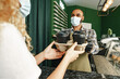 © fotofabrika - Male coffee shop worker giving ready order to the client wearing face mask