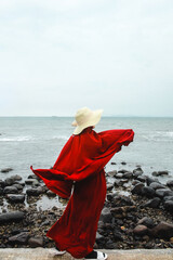 woman with red scarf and summer hat doing fashion pose at the beach