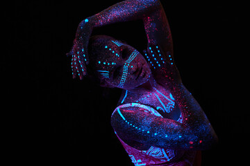 Art woman cosmos in ultraviolet light. Entire body is covered with colored droplets. Girl posing in the dark. Noise, out of focus